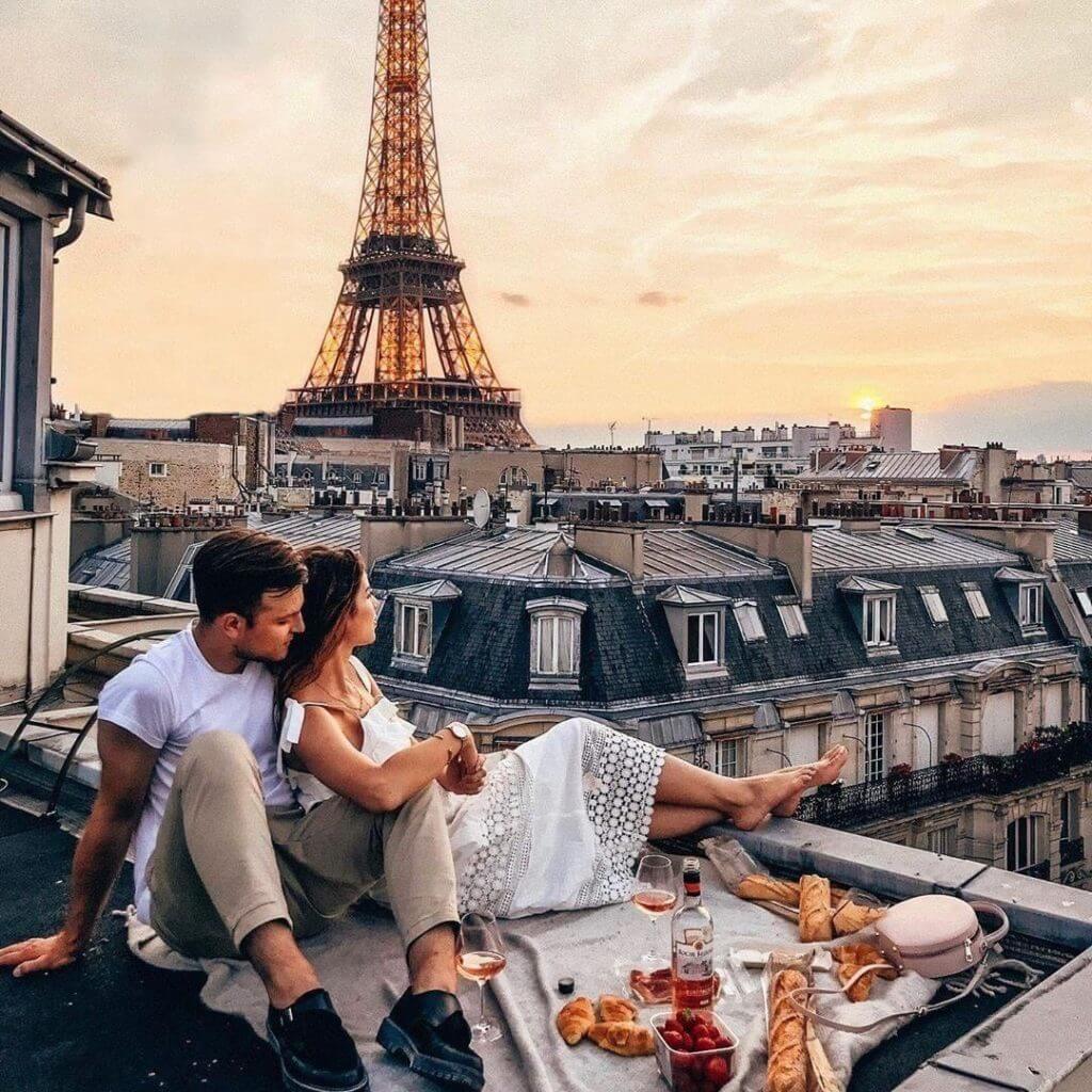 A couple sitting on a balcony with the Eiffel Tower in the background; Travels, Flights, Hotels.