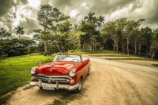 Red Car parked at road sited, there are trees behind - Car Hire in Sydney